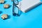 Scattered candies near optical glasses in black plastic frame and blank notepad lies on blue desk