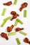 Scattered celery slices and Buffalo drumsticks on white background