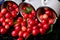 Scattered cherry from enamel cups. Cherries in iron cup on black background. Healthy, summer fruit. Cherries. Three. Close up.