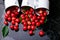 Scattered cherry from enamel cups. Cherries in iron cup on black background. Healthy, summer fruit. Cherries. Three. Top view.