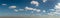 Scattered clouds across blue sky panorama