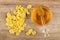 Scattered cornflakes, honey dipper on bowl with honey on table. Top view