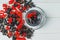 Scattered currant berries with drink on wooden background, flat lay