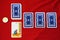 Scattered deck of tarot cards with one card upside down and candle on red background