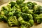 Scattered frozen broccoli on a round wooden board.