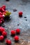 Scattered frozen red currants closeup lie on a rusty surface. copy space. vertical