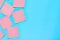 Scattered many pink square blank paper stickers on blue background. Copy space