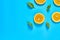 Scattered pieces of mandarin or orange and green leaves on blue background. Fruit purchasing concept