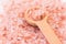Scattered pink Himalayan salt, wooden spoon, spa, health, wellness concept