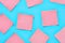 Scattered pink square blank paper stickers on blue background