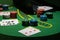 Scattered poker chips and cards on a green table with and laptop