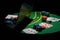 Scattered poker chips and cards on a green table with and laptop