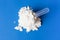 Scattered protein powder and scoop on blue background, top view