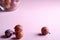 Scattered ripe sweet plum fruits close to glass bowl with plums on pink background, soft light, copy space, selective focus