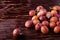 Scattered ripe sweet plum fruits on dark moody wood table background, soft light, copy space