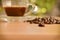 scattered roasted coffee beans on wooden table and a cup of coffee background