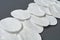 Scattered round cotton pads for hygiene lies on dark concrete table