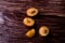 Scattered sliced half ripe sweet plum fruits with water drops on dark moody wood table background