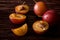 Scattered sliced half ripe sweet plum fruits with water drops on dark moody wood table background