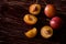 Scattered sliced half ripe sweet plum fruits with water drops on dark moody wood table background