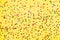Scattered star shaped colorful glittering confetti over yellow background.