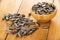 Scattered sunflower seeds and bamboo bowl with sunflower seeds on table