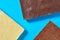 Scattered three various whole porous chocolate bars lies on blue table on kitchen. Top view