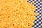 Scattered Uncooked Chifferi Rigati Pasta on Black Checkered Towel