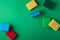 Scattered yellow, green, red, blue sponges on green colored paper background, copy space, top view, flat lay