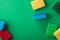 Scattered yellow, green, red, blue sponges on green colored paper background, copy space, top view, flat lay