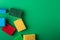 Scattered yellow, green, red, blue sponges on green colored paper background, copy space, top view, flat lay