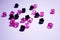 A scattering of beads on a white background, a sheet. Crystals. Iridescent and shiny pink and black beads. Materials for needlewor