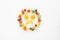 A scattering of many small different fruits on a white background. Emoji sad smile. Minimalism.