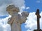 Scene in a cemetery: close-up of an old stone statue of a little angel with wings praying.