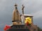 Scene in a cemetery: tomb with the statue of Our Lady and a crucifix.