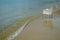 Scene of empty chair in white rattan sitting on sand beach with curved soft wave in shade of blue and clear sea water background