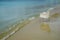 Scene of empty chair in white rattan sitting on sand beach with soft wave, shades of blue and clear sea water background