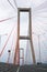 Scene of the famous Suramadu Bridge and its red suspension steel cables with lamp post on road and cloudy sky background.