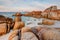 Scene of giant granite rock boulders covered in orange and red lichen at the Bay of Fires in Tasmania, Australia