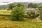 A scene of valleys and forests and a farm house.