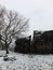 Scene with winter snow falling on a single tree and large rocky outcrop or boulder with path in west yorkshire england