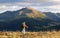 Scenery autumn sunny day. There is a tourist standing in sport clothes watching the mountains peak, sky with clouds