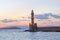 Scenery with beautiful ancient lighthouse surrounded by the sea. Sunset sky with pink light. Seaport Chania, Creete island, Greece