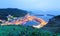 Scenery of coastal highway crossing the harbor of a fishing village with lights of fishing boats on the sea ~