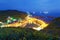 Scenery of coastal highway crossing the harbor of a fishing village with lights of fishing boats on the sea