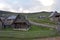 Scenery image of mountain shepherd village huts with view of forest and blue sky in the background