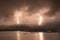Scenery lightning strike during rainy storm hitting the mountain near lake