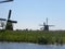 Scenery of mills near a river on a blue clear sky background