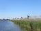 Scenery of mills near a river on a blue clear sky background