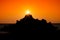 Scenery of the setting sun overlapping the rocks and the sky dyed red